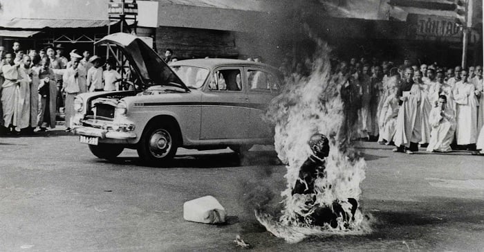 Monk burning in front of car and crowd of people