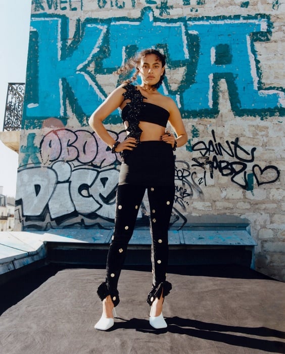 Woman posing in front of graffittied wall