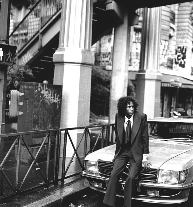 Man in suit leaning on a car bonnet