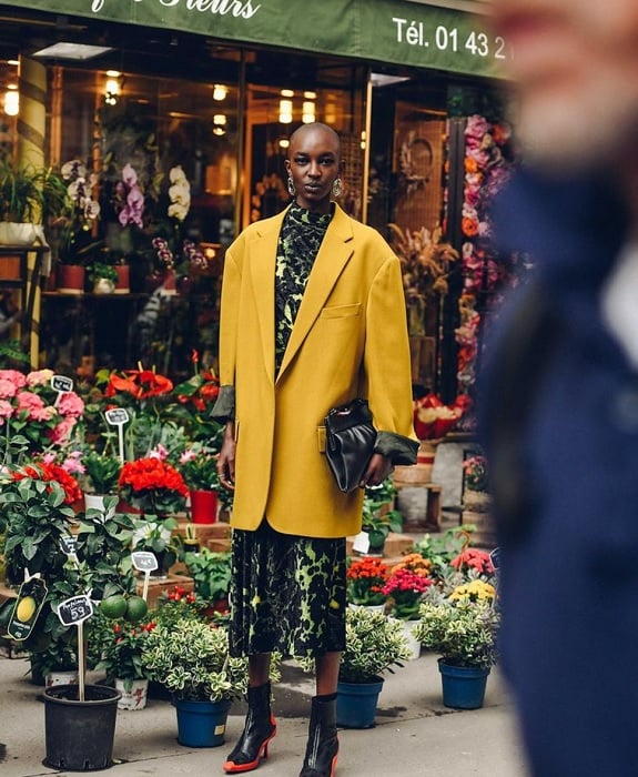 Woman in yellow coat in front of flower shop