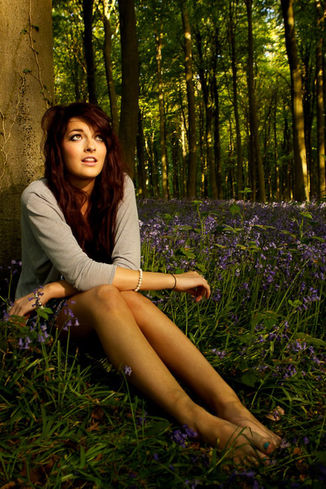 An outdoor natural light portrait of a female model sitting under a tree