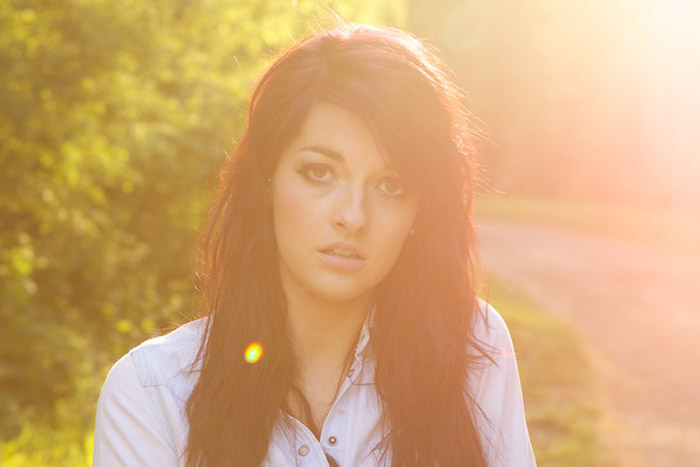 Outdoor portrait of a female model featuring artistic lens flare