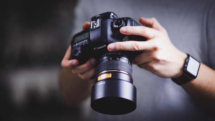 Um fotógrafo alterando configurações em uma câmera DSLR da Canon
