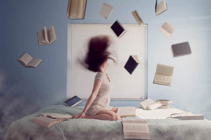 Ένα εννοιολογικό πορτρέτο ενός κοριτσιού στην κρεβατοκάμαρά της που περιβάλλεται από πετώντας βιβλία