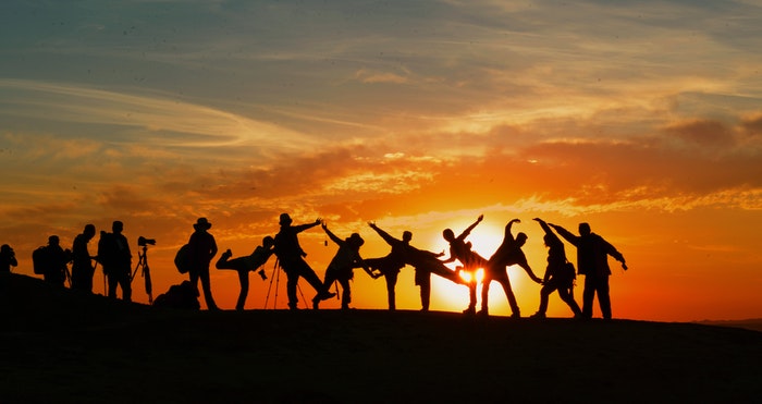 Um grupo de fotógrafos em silhueta contra um pôr do sol