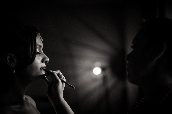 Un retrato en blanco y negro con poca profundidad de foco de una mujer aplicando el maquillaje fotografiado con un objetivo prime