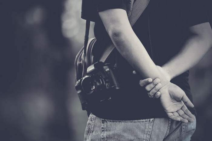 Un primer plano en blanco y negro de un hombre con una cámara discreta con un objetivo de 50mm para hacer fotos callejeras cándidas