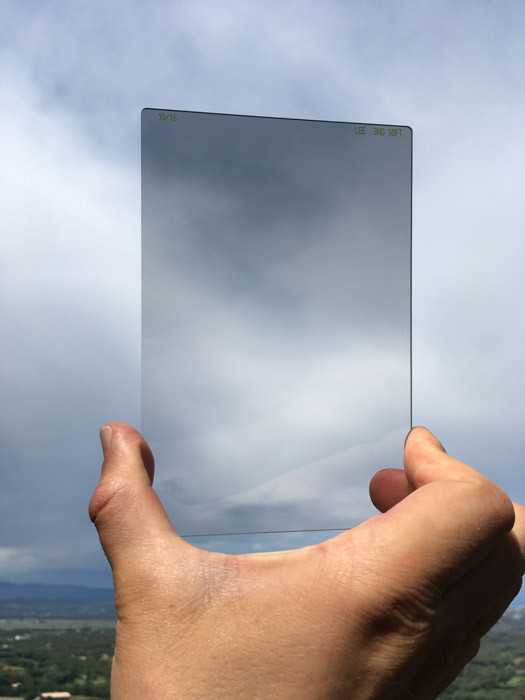 Uma pessoa com um filtro ND graduado para fotografia de paisagem até o céu