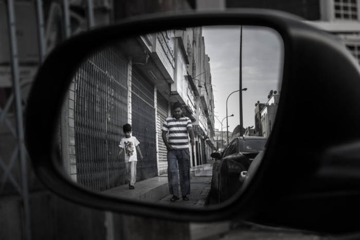 O reflexo de um pai e filho caminhando por uma rua