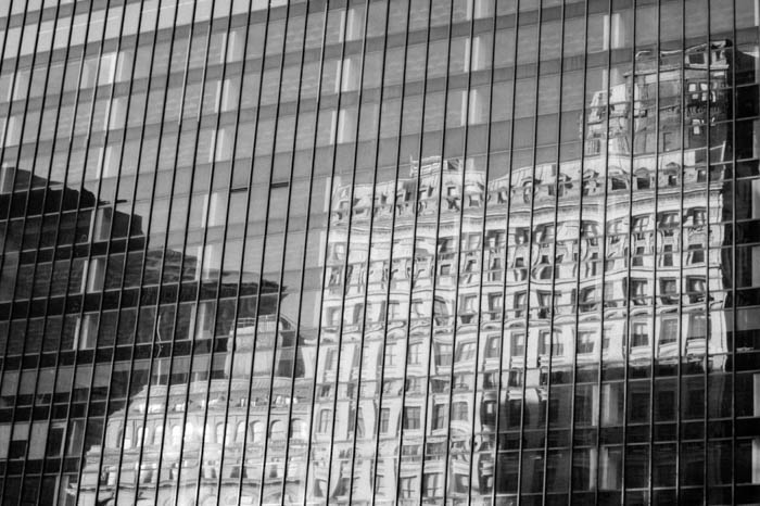 Reflecția alb-negru a unei clădiri în ferestrele de sticlă ale unei alte clădiri 