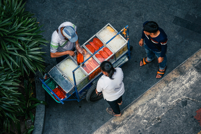Uma fotografia de rua de um vendedor de comida servindo comida em seu carrinho 