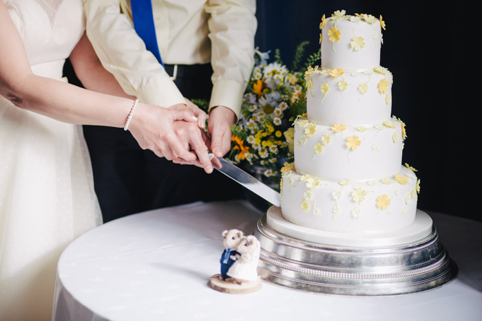 Fotografia de casamento do casal cortando um bolo.