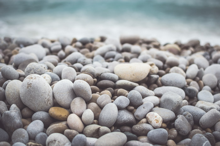 Una foto de cerca de rocas coloridas con efecto bokeh de las olas en el fondo