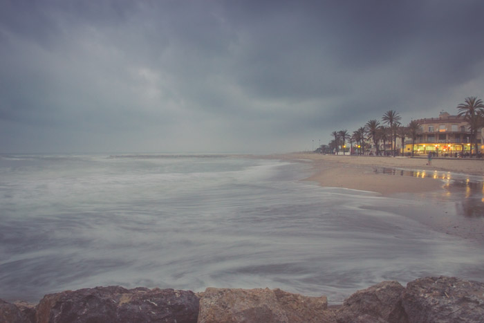 een kustgezicht gefotografeerd tijdens een storm met een strandhuis rechts van het frame