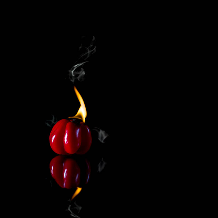 Foto de comida creativa de un pimiento rojo que está tan caliente que está en llamas