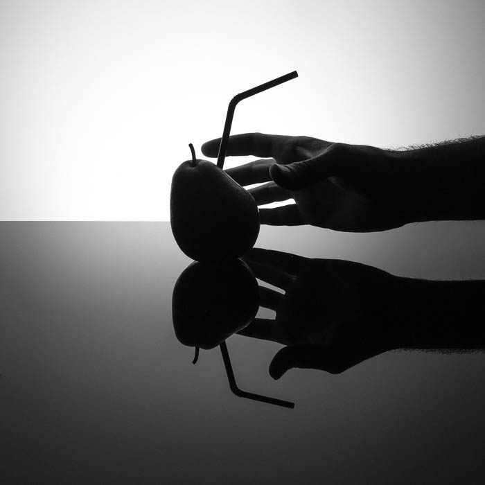 Foto oscura de estilo comercial con una pajita clavada en una pera