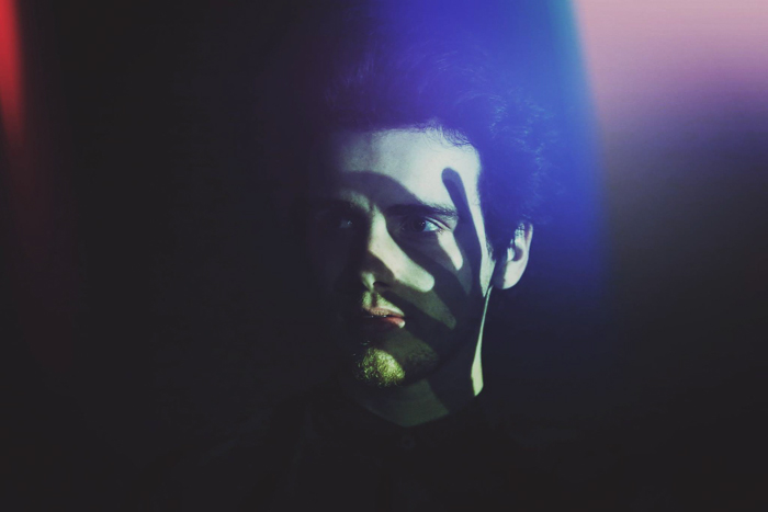 Retrato nocturno de un hombre con la sombra de una mano en su rostro