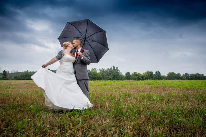 A noiva e o noivo posam beijando sob um guarda-chuva