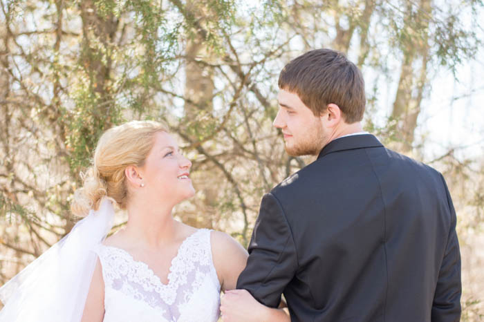 Noiva e noivo posam braço no braço ao ar livre