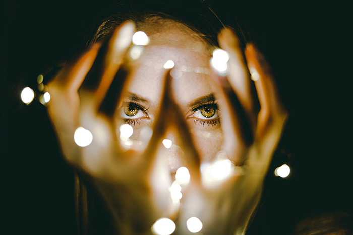 Portrait of a girl holding fairy lights to her face