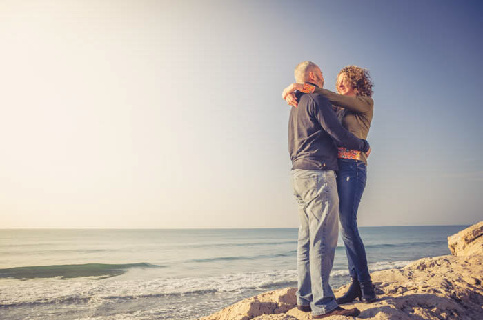 Um casal posando em pedras na praia