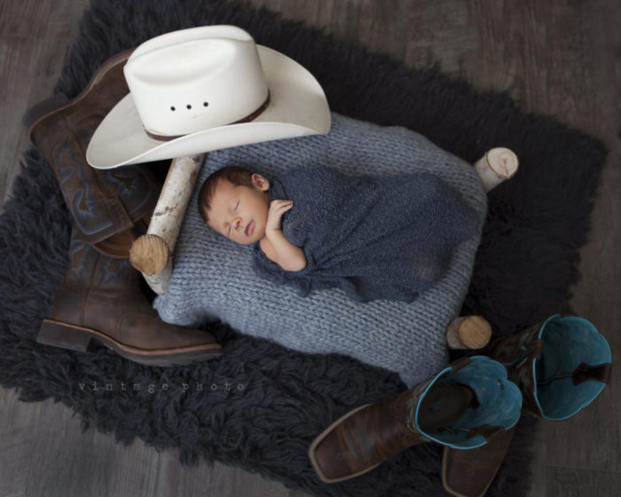 Um recém-nascido dormindo rodeado de acessórios.