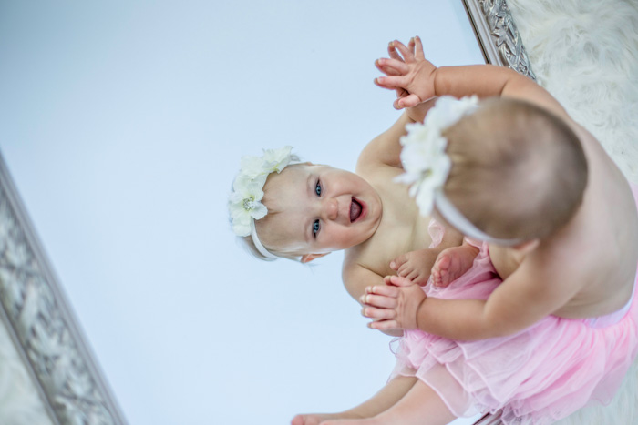 Um lindo retrato recém-nascido de um bebê olhando no espelho