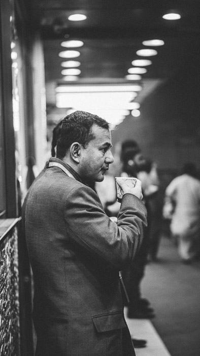 Foto di strada in bianco e nero di un uomo che beve un caffè. Fotografia in condizioni di scarsa luminosità.