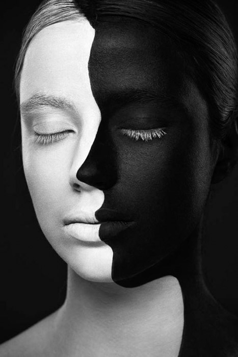 Portrait d'un visage de femme peint moitié noir et moitié blanc sur fond noir comme exemple de juxtaposition de couleurs.