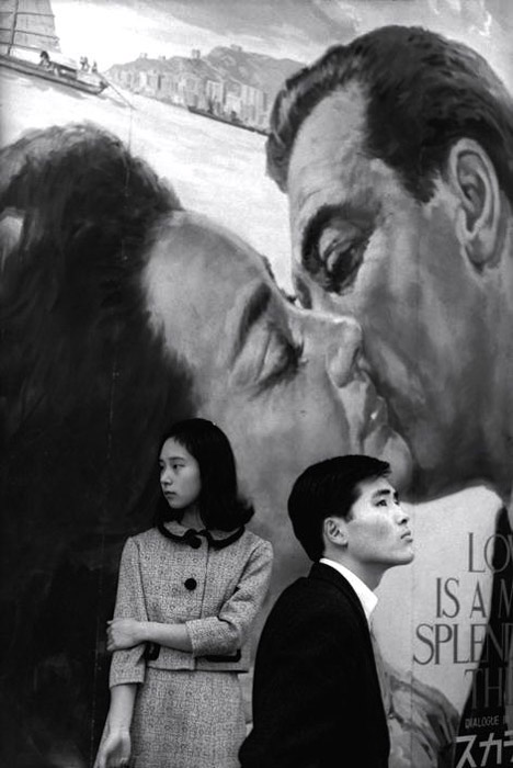 Henri Cartier-Bresson photo d'un homme et d'une femme debout juxtaposés sur un fond peint d'un couple s'embrassant.