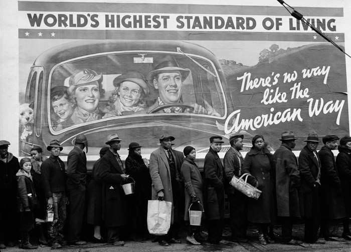 foto a preto e branco de muitas pessoas em fila por comida no primeiro plano justaposto com um cartaz afirmando 'o mais alto padrão de vida do mundo'. exemplos de justaposição'world's highest standard of living'. juxtaposition examples