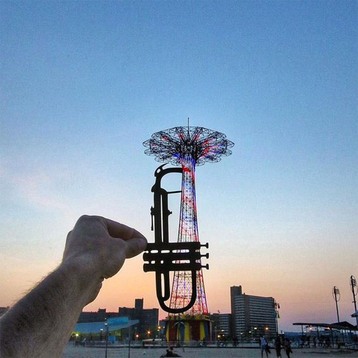 Photo du photographe s'étendant devant l'objectif wrm et plaçant une version découpée d'une trompette dans une photographie