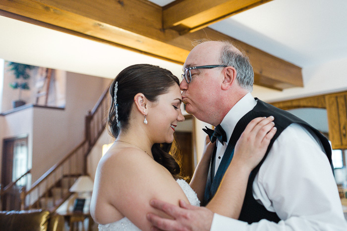 Beautiful moment of father kissing the brides head captured by the wedding photographer