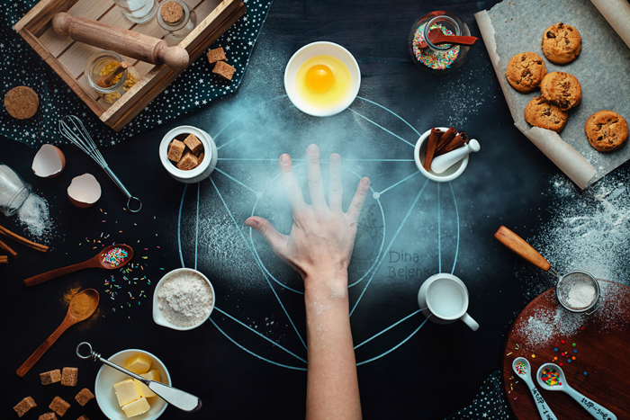 Foto dall'alto di una mano tesa nel mezzo di una divertente disposizione fotografica di cibo su sfondo scuro - idee di fotografia still life.