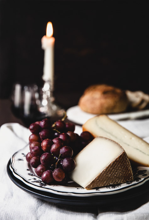 Still life photography of cheese and grapes on a plate.
