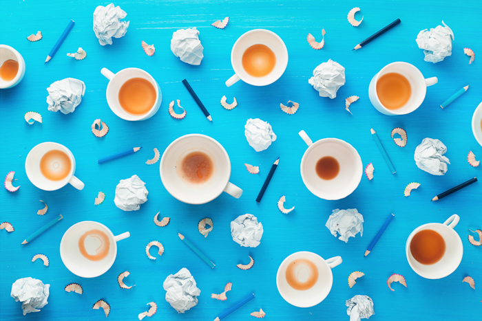 Ideas creativas de fotografía de bodegones con tazas de café vacías, bolas de papel arrugado y virutas de lápiz sobre un colorido fondo azul. Concepto de inspiración minimalista.