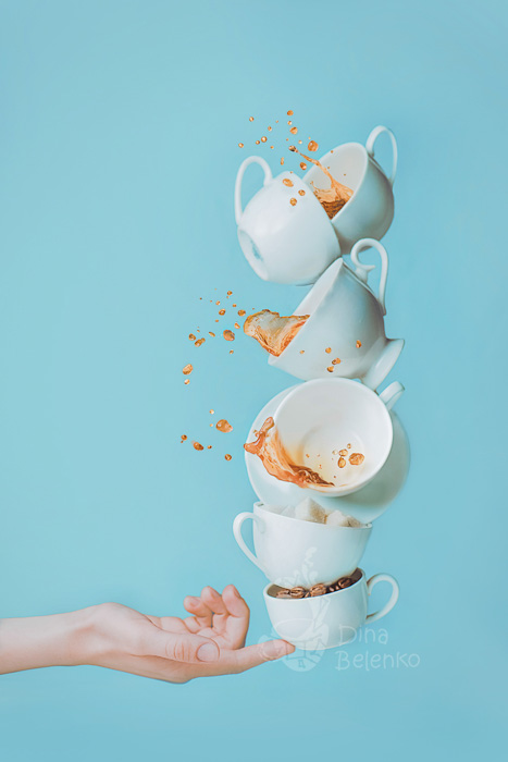 Fun Kaffee Fotografie Schuss von sechs fallenden Tassen auf der Spitze jemandes Finger ausgeglichen