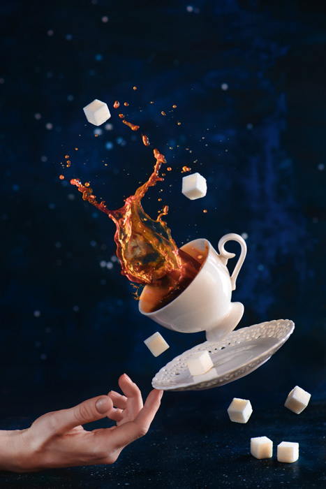 Morsom kaffe fotografering skutt av en fallende kopp, skål og sukker kopper balansert på tuppen av noens finger