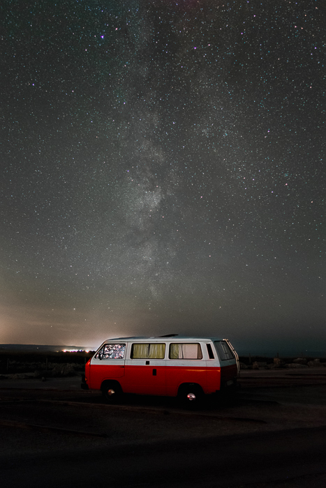 Imagem de um motorhome vermelho estacionado sob um céu estrelado impressionante depois de usar o empilhamento de foco para ajudar a remover trilhas de estrelas