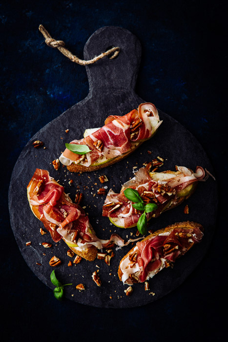Bidikan atas prosciutto crostini dengan pecan dalam gaya fotografi makanan gelap