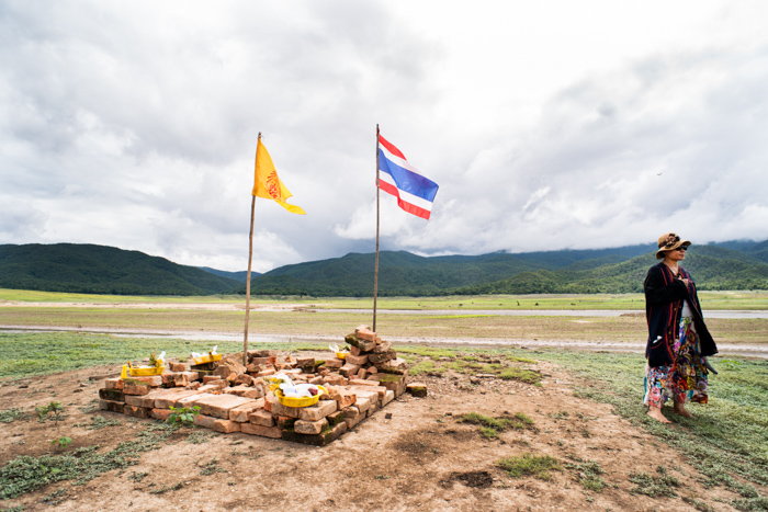 a woman stands beside a make shift shrine near the ruins of the Buddhist temple in the dry lake bed at Doi Tao, Chiang Mai province, Thailand.