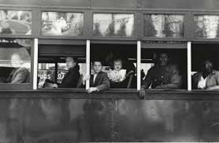 A black and white Robert Frank photograph of passengers looking out a bus window