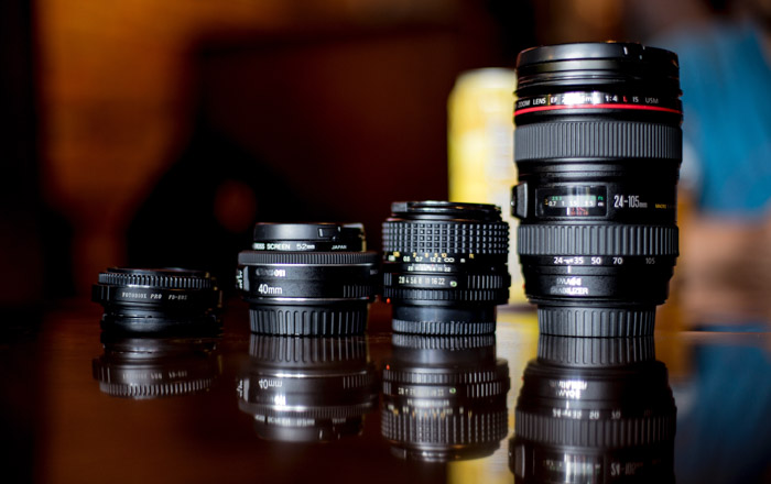 quatro tipos diferentes de lentes fotográficas em uma mesa com reflexos 