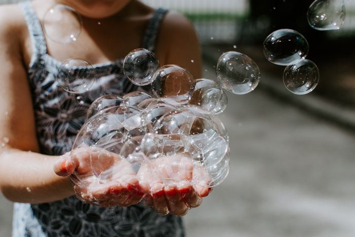 foto de uma garota segurando bolhas de sabão em suas mãos