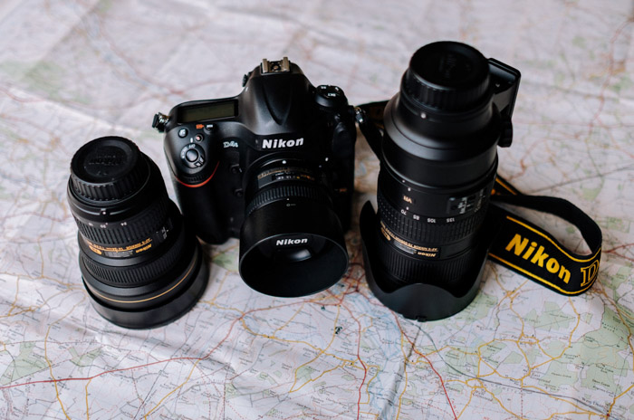 Uma câmera Nikon DSLR e duas lentes grande angular diferentes sobre um mapa