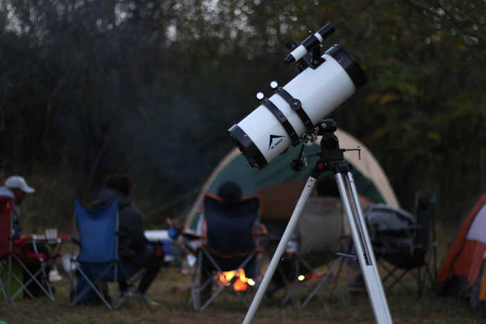 Um telescópio em primeiro plano de um acampamento.