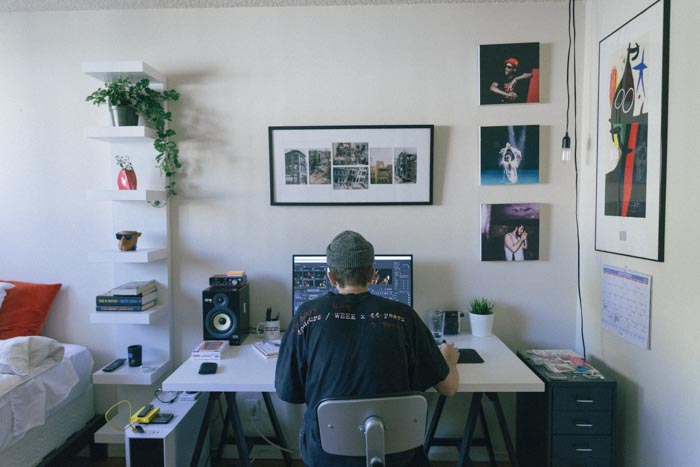 Um homem editando fotos em um laptop em um escritório doméstico