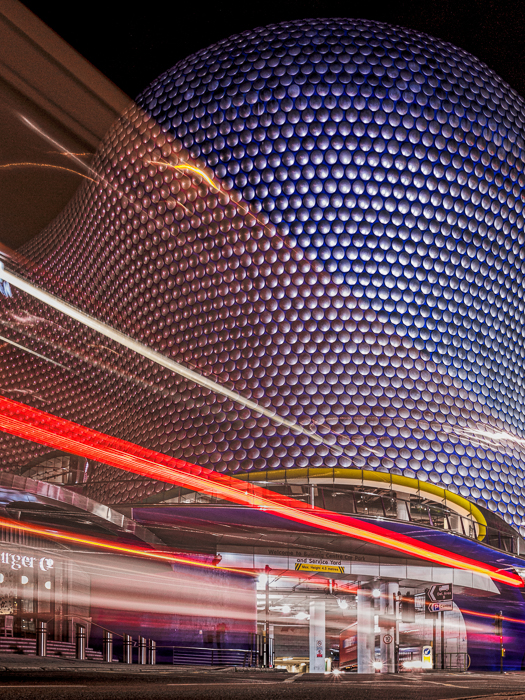 Le centre des arènes de Birmingham avec les sentiers lumineux d'un bus à deux étages passant devant