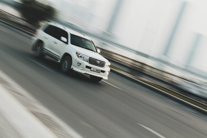 Un coche blanco conduciendo, el fondo es un desenfoque creativo que demuestra la velocidad de obturación y sus usos