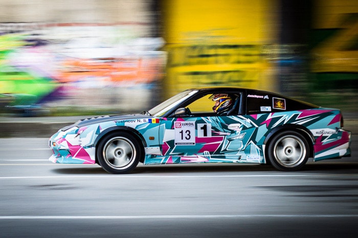 Un colorido coche de carreras conduciendo con un fondo de desenfoque de movimiento